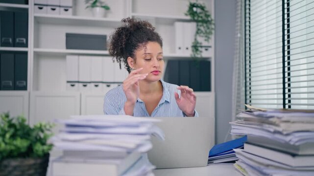 Latina businesswoman working and reviewing documents on desk at office. 