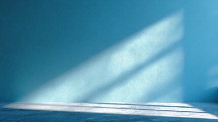 Room features a blue wall with textured surface concrete floor  shadows from a window highlighting the rooms simple aesthetic