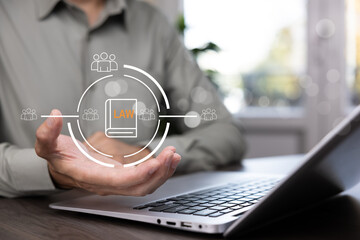 Law and legal regulation concept with businessman using laptop and digital law book icon. Modern justice, compliance, online legislation, data protection, and corporate governance.