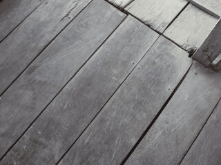 A close-up diagonal view of old, weathered gray wooden floorboards showing texture and grain.
