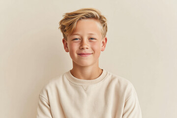 Cheerful young boy smiling against beige background