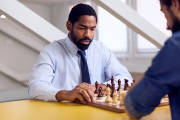 African Man in Formal Attire Concentrating on a Chess Game in a Bright Room
