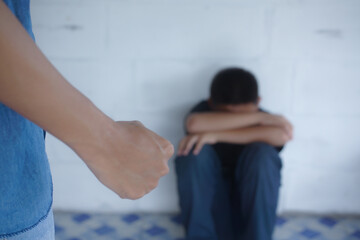 A frightened, crying child is sitting in the corner of the room. Violence against children in the...