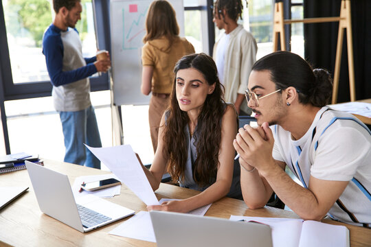 Stylish coworkers collaborate on a project in a vibrant office space during a busy workday