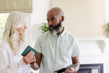 African American man and woman discussing wedding plans at home, holding tablets