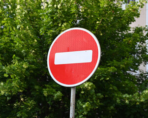 No entry sign stands prominently against a green backdrop on a sunny day
