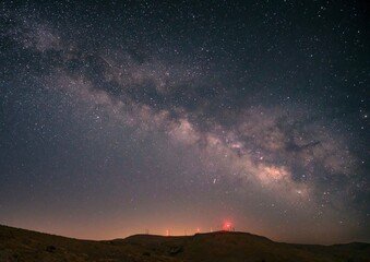 Milky Way over hills with red lights at night.