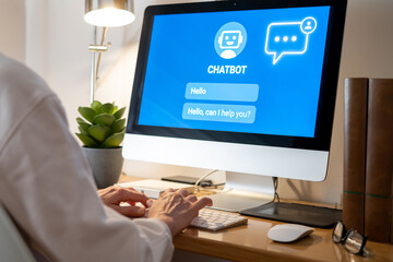Office worker is typing on a computer keyboard and interacting with a chatbot displayed on the screen, showcasing the future of customer support and automation through ai