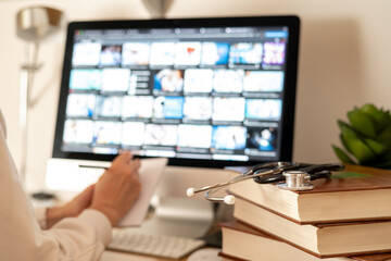 Medical student taking notes during an online course, surrounded by medical books and a stethoscope, illustrating the fusion of technology and traditional learning in healthcare education