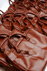 A stack of tan leather laptop bags with an elegant design, perfect for leather product catalog designs.