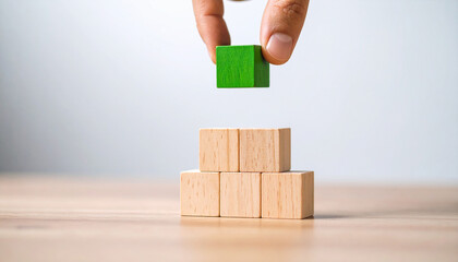 Cubo verde sobre pila de bloques de madera simbolizando sostenibilidad ecología crecimiento éxito empresarial futuro responsable innovación equilibrio estrategia y desarrollo positivo en concepto visu