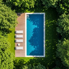 Aerial view of luxury backyard swimming pool with pristine blue water, Modern Backyard Swimming Pool with Lounge Chairs – Aerial View surrounded by green lawn, trees. Two white lounge chairs sit on wo