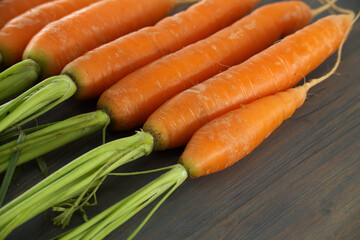Fresh Orange Carrots with Green Tops on Wooden Surface