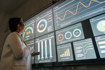 Fototapeta premium Professional reviews interactive data dashboard with charts and graphs on a large digital screen in a modern office, illustrating analytics, performance tracking, and decisions.