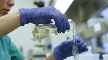 Scientist in a laboratory carefully pouring a chemical liquid solution from a beaker into a test tube for an experiment - Powered by Adobe