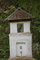 A small white building with a cross on top and a window