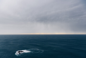Dramatic seascape with rocky islet and stormy horizon