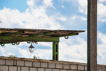 Sheltered outdoor area under wooden canopy with light fixture against blue sky