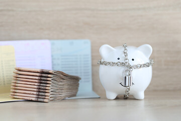 Blocked accounts,Piggy bank with padlock and banknotes on wooden background,Account passbooks were locked or Account frozen concept