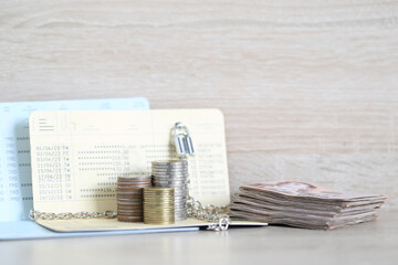 Blocked accounts,Stack of coins money and banknotes with banking account book on wooden background,Account passbooks were locked or Account frozen concept