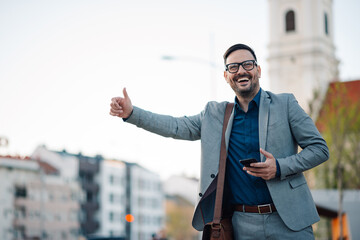 Cheerful businessman hailing a taxi in the city center