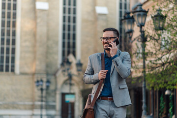 Businessman walking and talking on phone in city center