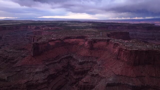 Aerial view of the Canyonlands National Park, where the deep red hues of the layered rock formations dramatically contrast with the stormy sky, Moab, Utah, United States.