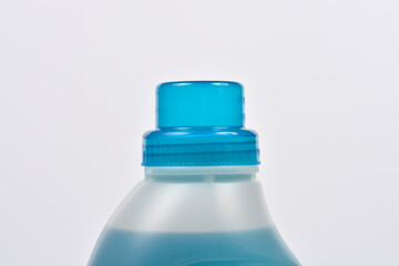 A horizontal, close-up studio shot of the top of a frosted laundry detergent bottle with a translucent blue cap against a white background