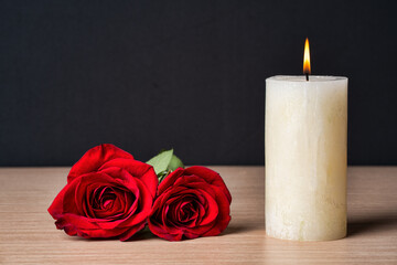 Burning candle and red roses lily on dark background with copy space. Sympathy card