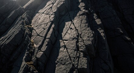 Jagged rock face with fractures, sunlit top and shadowy lower portion