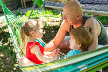 Cheerful family, a little girl and boy with grandfather  having fun in the park