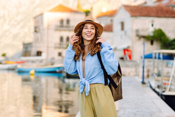 Portrait of a young woman wearing a hat and carrying a briefcase strolling along the sea in a...