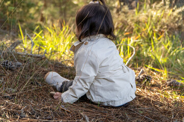 Unrecognizable toddler girl exploring the autumn forest floor showcasing the importance of environmental education