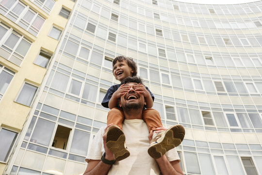 Father and son walking outdoors laughing in city near high rise building