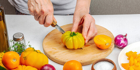 A woman is preparing a tomato salad. Ripe vegetables, herbs, aromatic spices, olive oil