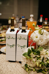 Two bottles of wine stand among various dishes and soft drinks on a banquet table during a holiday
