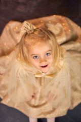 Fototapeta premium Little Princess in Golden Dress Covering Face Shyly
