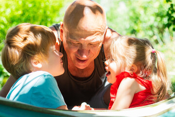 Cheerful family, a little girl and boy with father smiling and having fun outdoors in summer nature