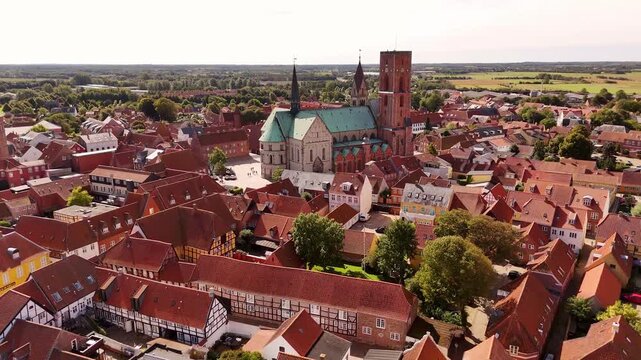 Aerial view of the majestic Ribe Cathedral amidst red-roofed buildings, creating a striking contrast with lush greenery, Ribe, Denmark.