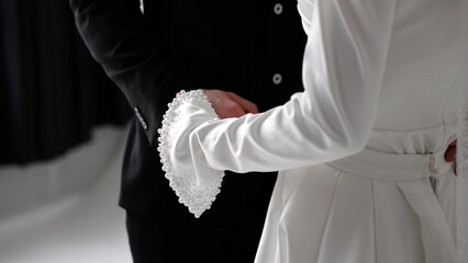 Naklejka premium Groom and bride holding hands, showing wedding attire and pearls