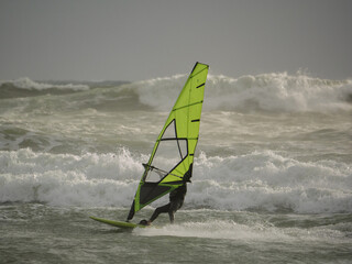 Water Sport Activity - Windsurfer Riding a Wave in Rough Sea on a Windy Day