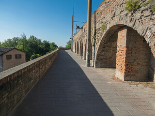 Ancient Brick Arches Beside Sunny Paved Pathway Under Bright Blue Sky, Bologna, Italy