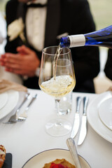White wine being poured into a glass during the wedding dinner with elegant serving.