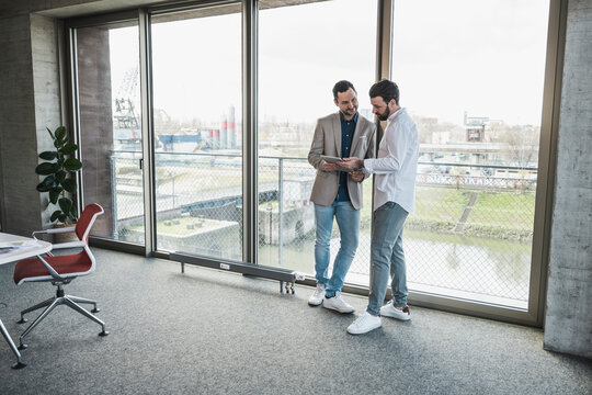 Business colleagues discussing over tablet computer in office