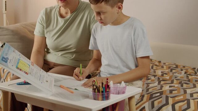 Focused child writing homework with parent support