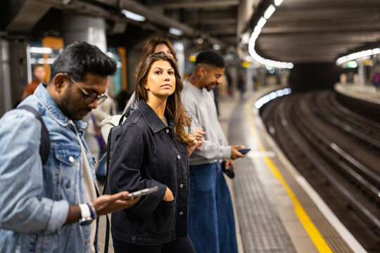 People waiting on London underground platform with mobile phones