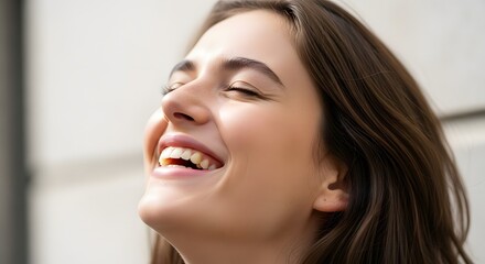 Joyful woman with closed eyes laughing heartily in a bright setting.