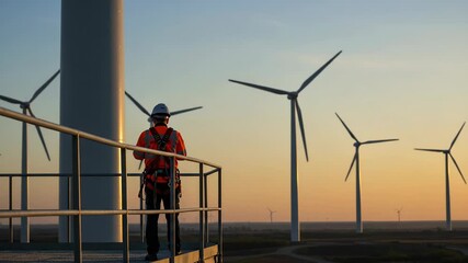 Wind turbine technician inspecting wind farm at sunset - Powered by Adobe