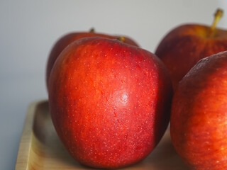 Fresh red apples on a wooden tray, close-up