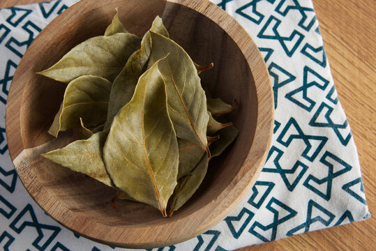 Dried bay leaves in a wooden bowl on the table - Powered by Adobe